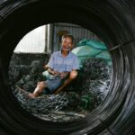 Portrait of a senior man smiling while handling wires in an industrial setting.