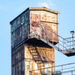 Rusted industrial building with stairs under a blue sky in Duisburg, Germany.